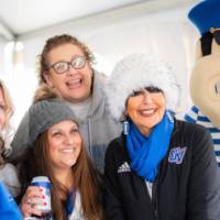 President Mantella and Louie smile with alumni in the Tailgate Tent
